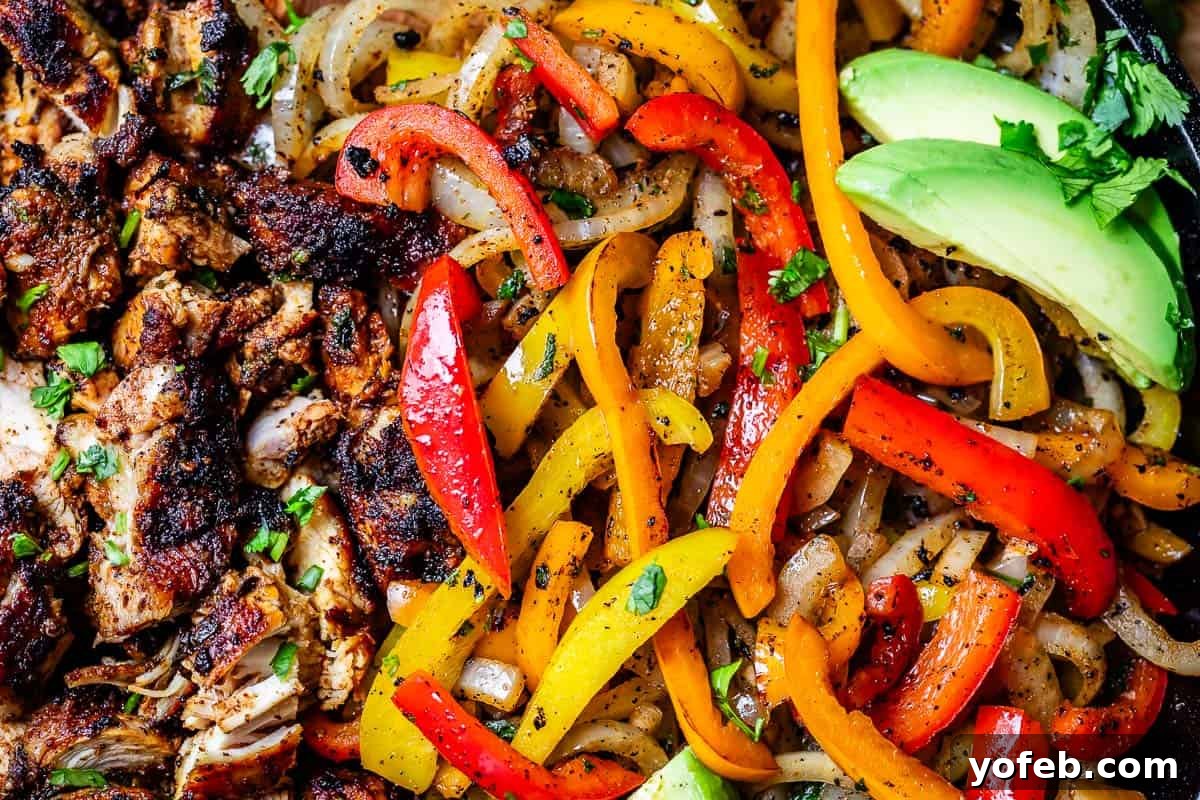 My Chicken Fajitas Awakening 21 close up of cooked chicken alongside sauteed onion and bell pepper, with avocado garnish.