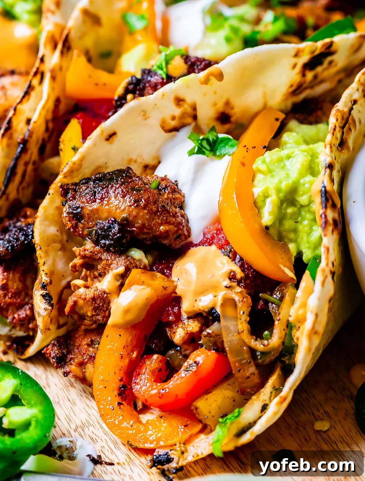 My Chicken Fajitas Awakening 25 close up of chicken fajitas in tortilla with peppers and onions, sour cream, cilantro.