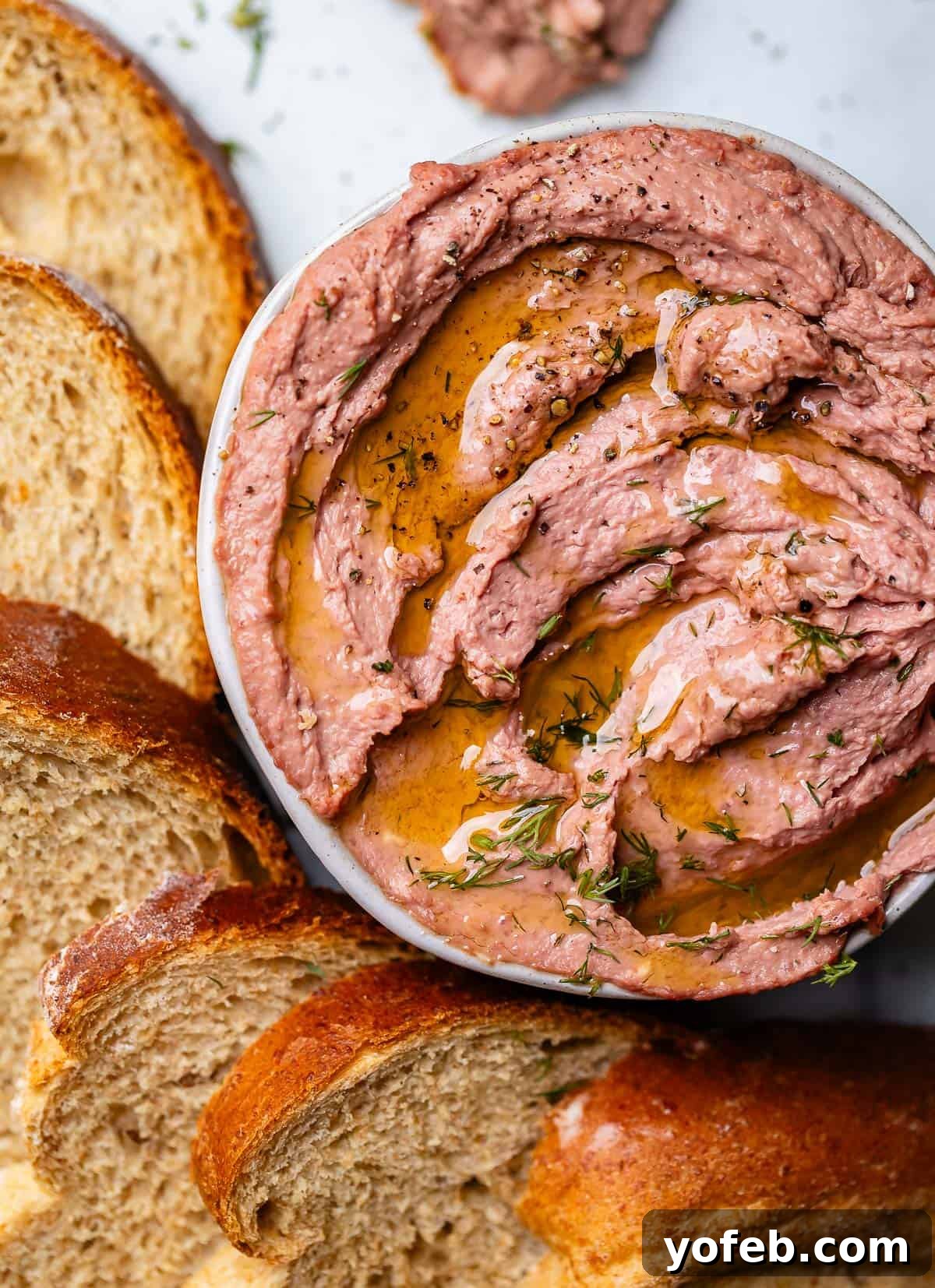 Liver pate in bowl surrounded by slices of rye bread.