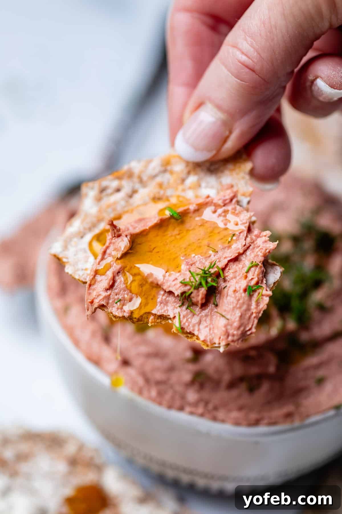 A square piece of homemade Swedish Flatbread generously spread with Liver Pâté, adorned with fresh dill and a delicate drizzle of olive oil.