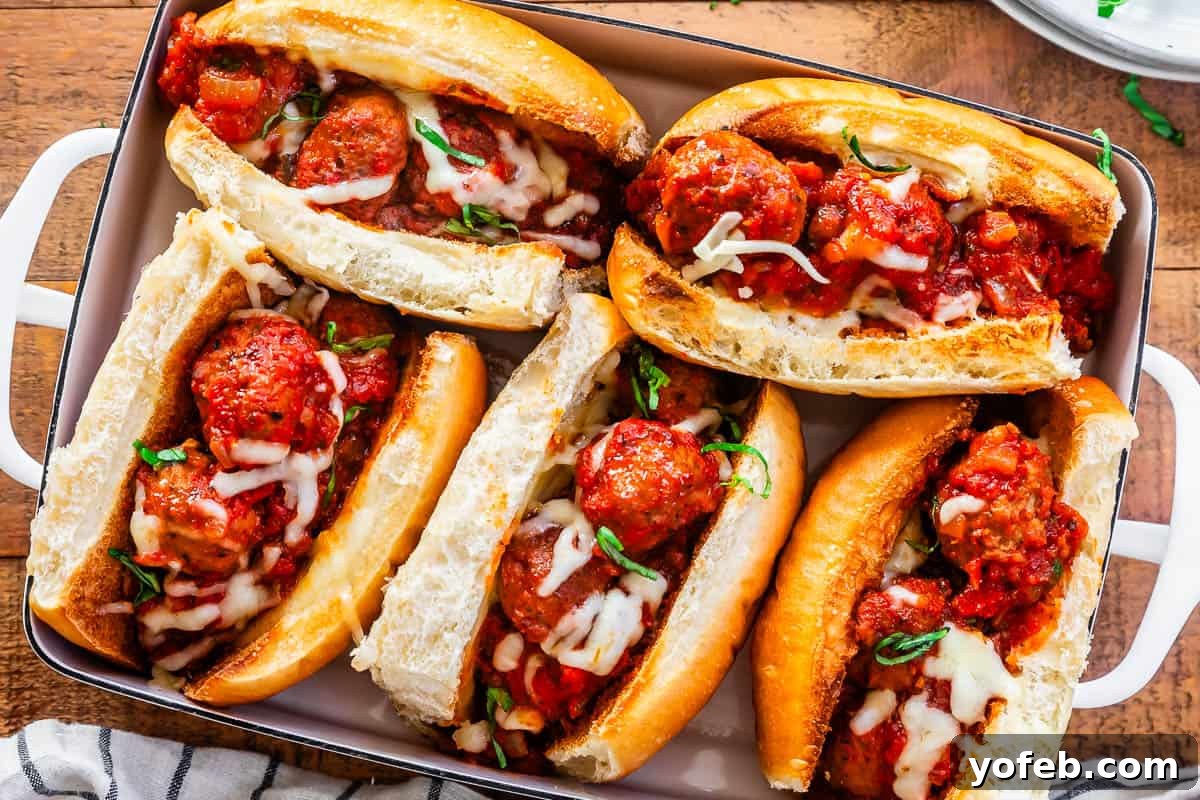 Laura's Ultimate Meatball Sub 12 Five partially assembled meatball subs, each filled with sauce and meatballs, neatly arranged in a 9x13 baking pan, ready for a final broil to perfectly melt the cheese topping.