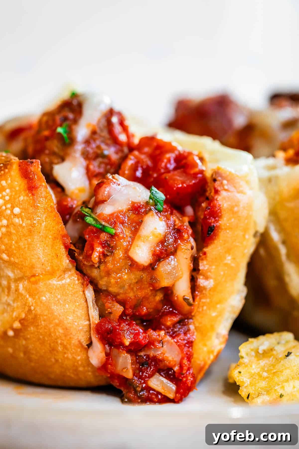 Laura's Ultimate Meatball Sub 4 A close-up, mouth-watering view of a meatball sub, revealing the rich sauce, tender meatballs, and stringy melted cheese within a perfectly toasted hoagie roll, inviting the first bite.