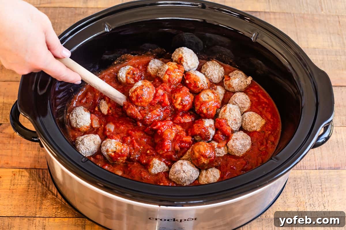 Laura's Ultimate Meatball Sub 9 Frozen meatballs being gently added to a slow cooker already filled with the rich, simmering tomato sauce, ready for a long, slow cook to infuse with flavor.