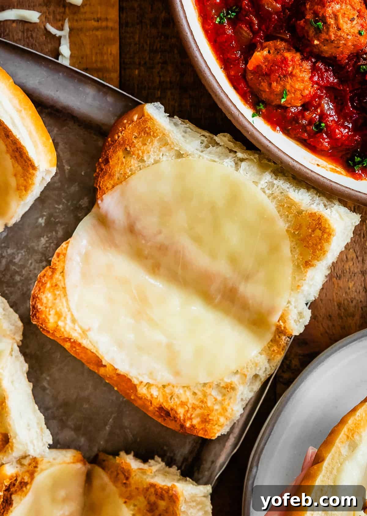 Laura's Ultimate Meatball Sub 10 A close-up view of a sturdy sub roll with a layer of glistening, melted Provolone cheese, achieved after a brief broil, forming a crucial barrier for the meatball filling.