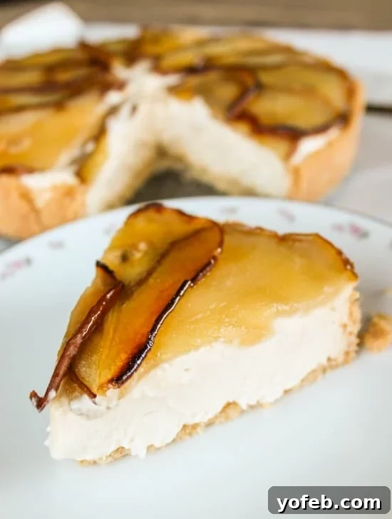 Roasted Pear and Maple Bliss Cheesecake 4 A wider shot of the maple cheesecake with roasted pears, showcasing its height and elegant presentation on a white cake stand.