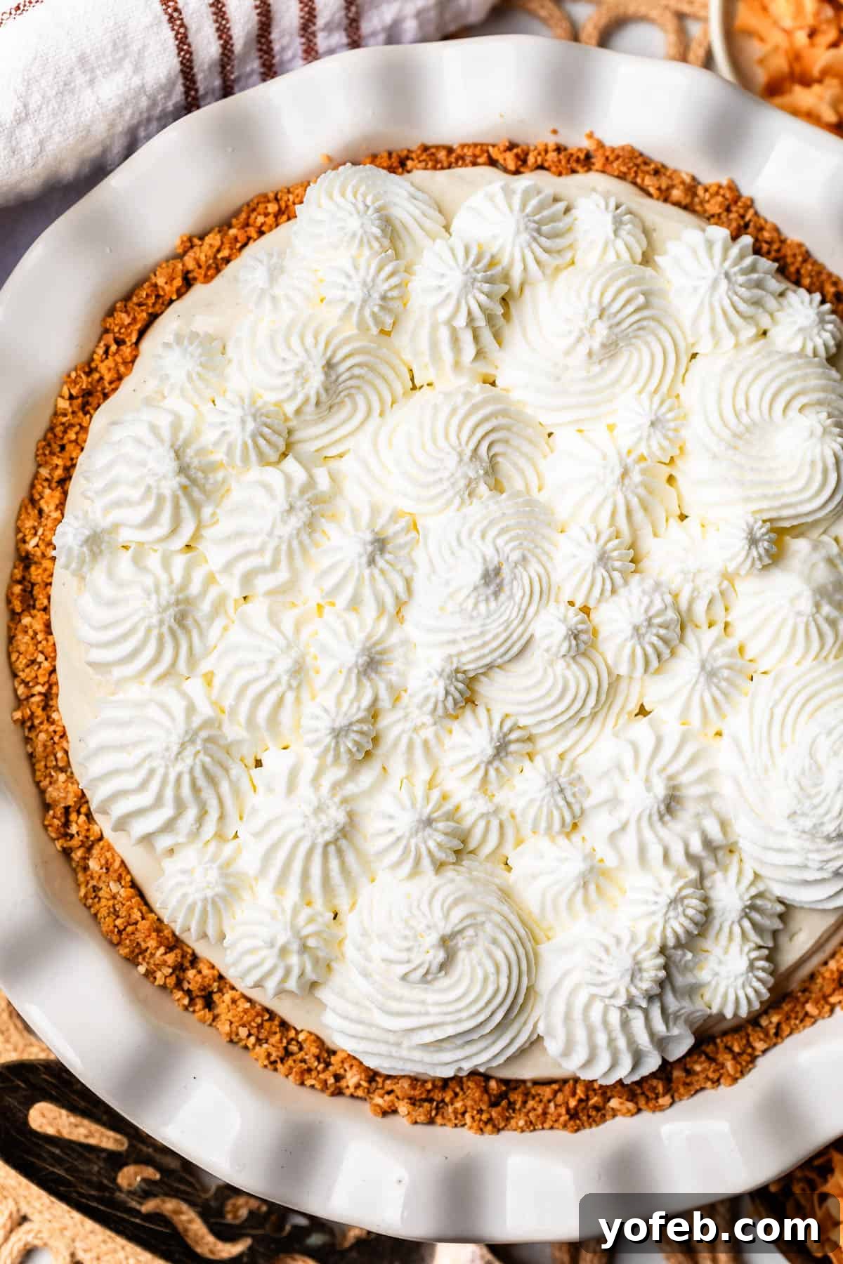 Luscious Caramel Swirled Coconut Cream Pie 20 looking down on a pie topped with whipped cream piped in swirls.