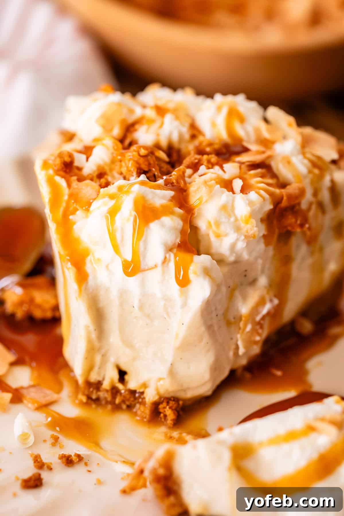 Luscious Caramel Swirled Coconut Cream Pie 25 half eaten slice of coconut cream pie on a white plate with caramel drizzle.