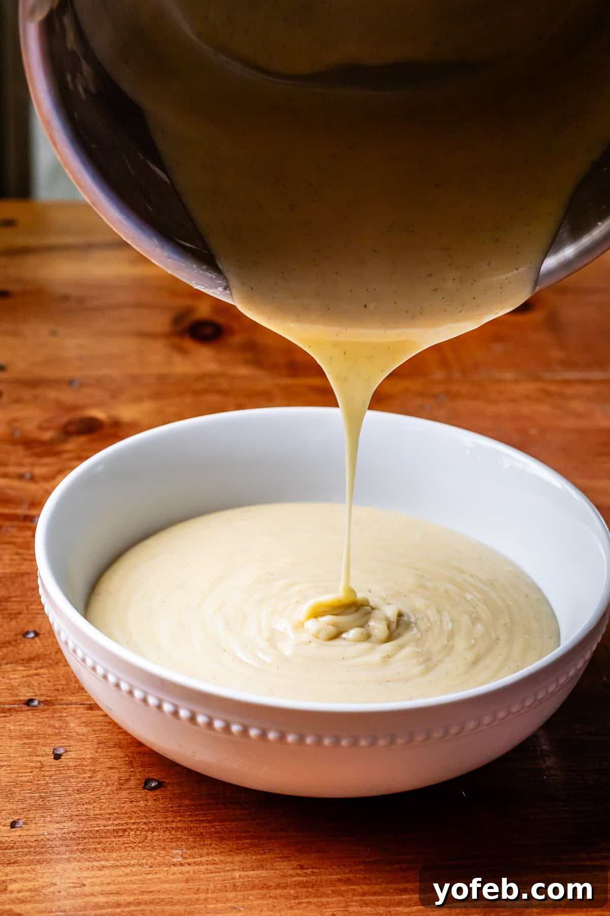 Luscious Caramel Swirled Coconut Cream Pie 10 pouring the cooked coconut custard from a metal pot to a ceramic bowl.