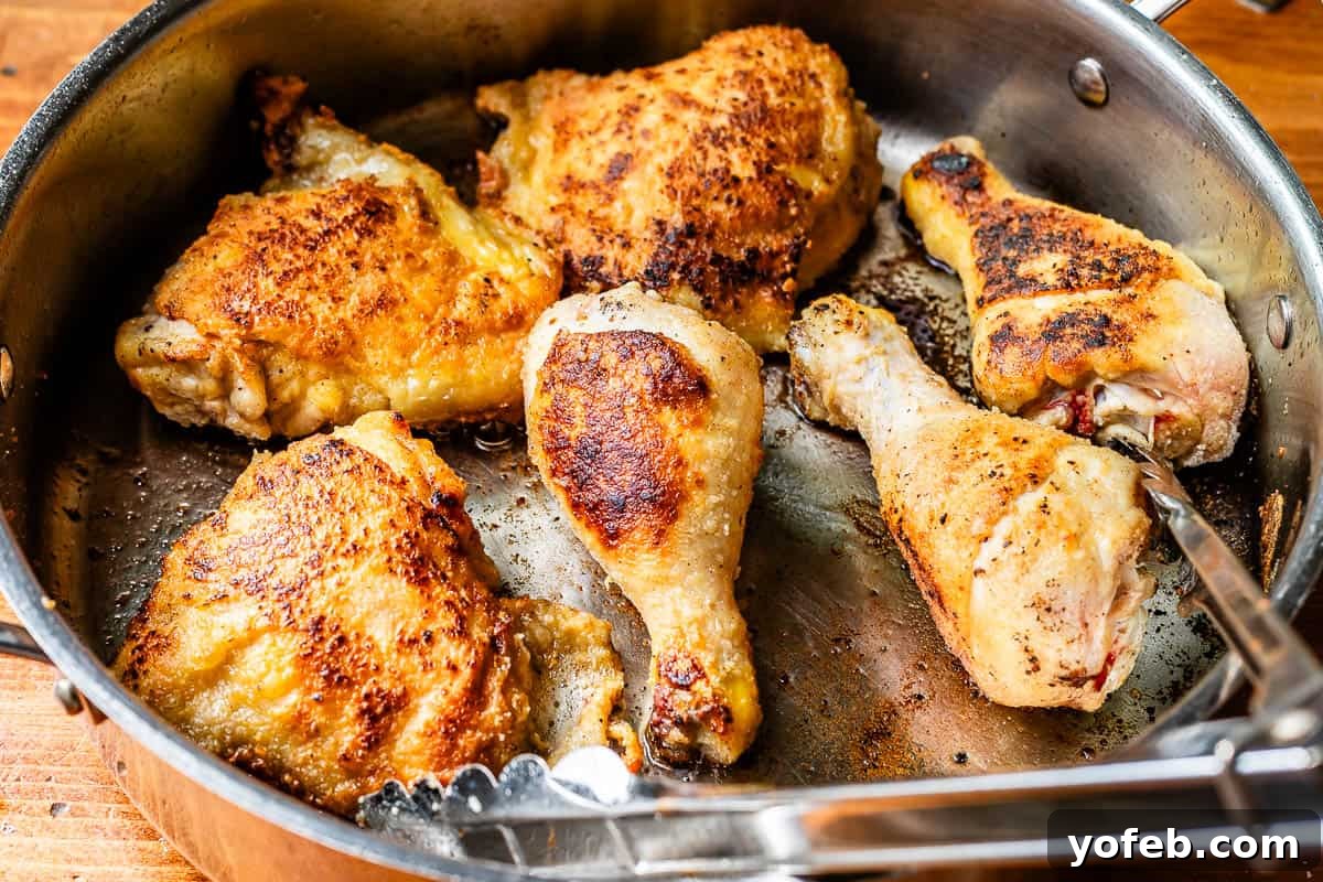 Grandma Georgia's Homestyle Chicken and Rice Bake 12 A large skillet contains three golden-brown seared chicken thighs and three drumsticks, arranged in a single layer, showcasing their crispy skin and readiness for the next step in the casserole preparation.