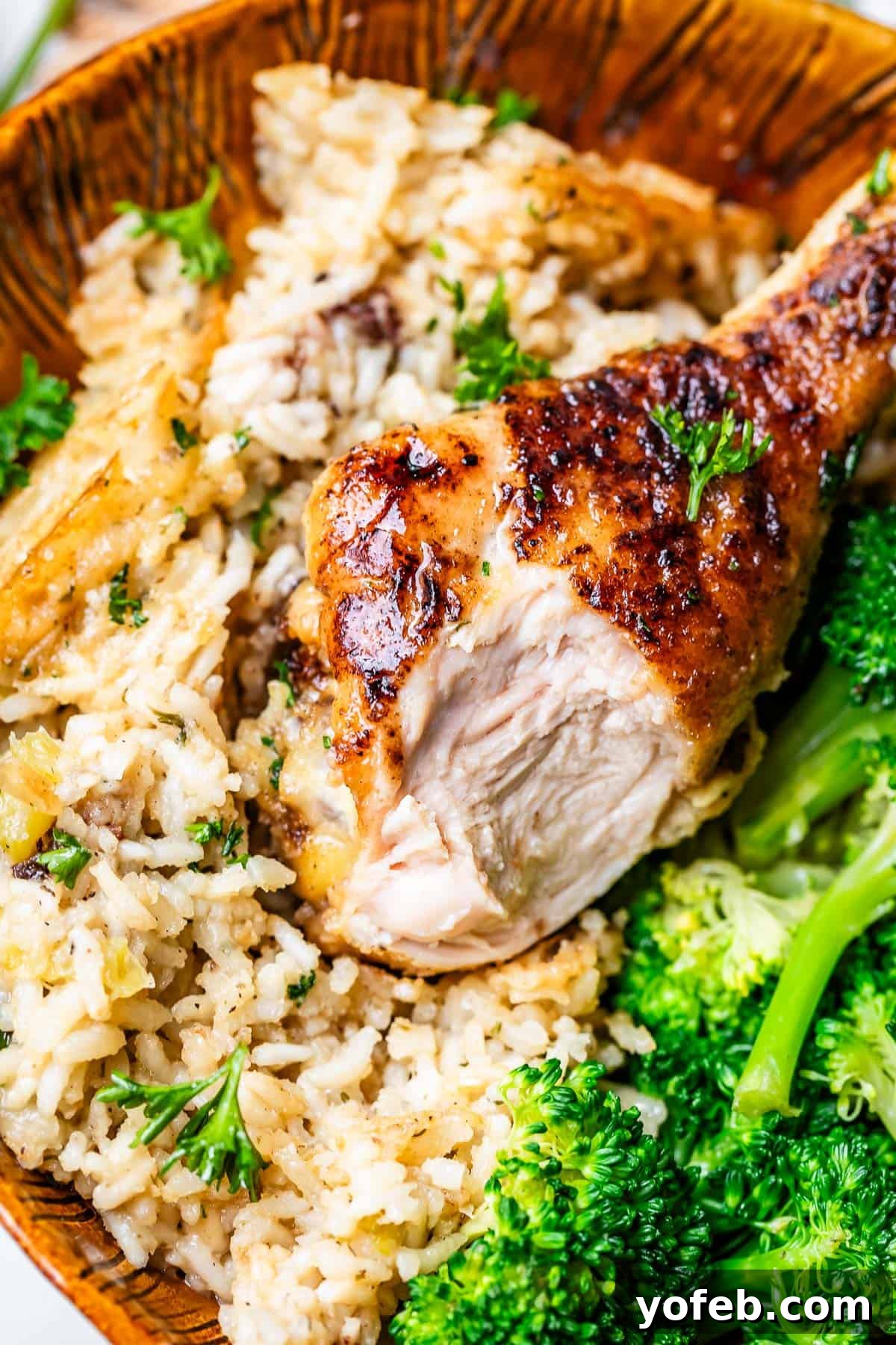 Grandma Georgia's Homestyle Chicken and Rice Bake 19 A close-up of a rustic wooden bowl filled with tender chicken, fluffy rice, and bright green broccoli, highlighting a perfectly balanced and comforting meal.