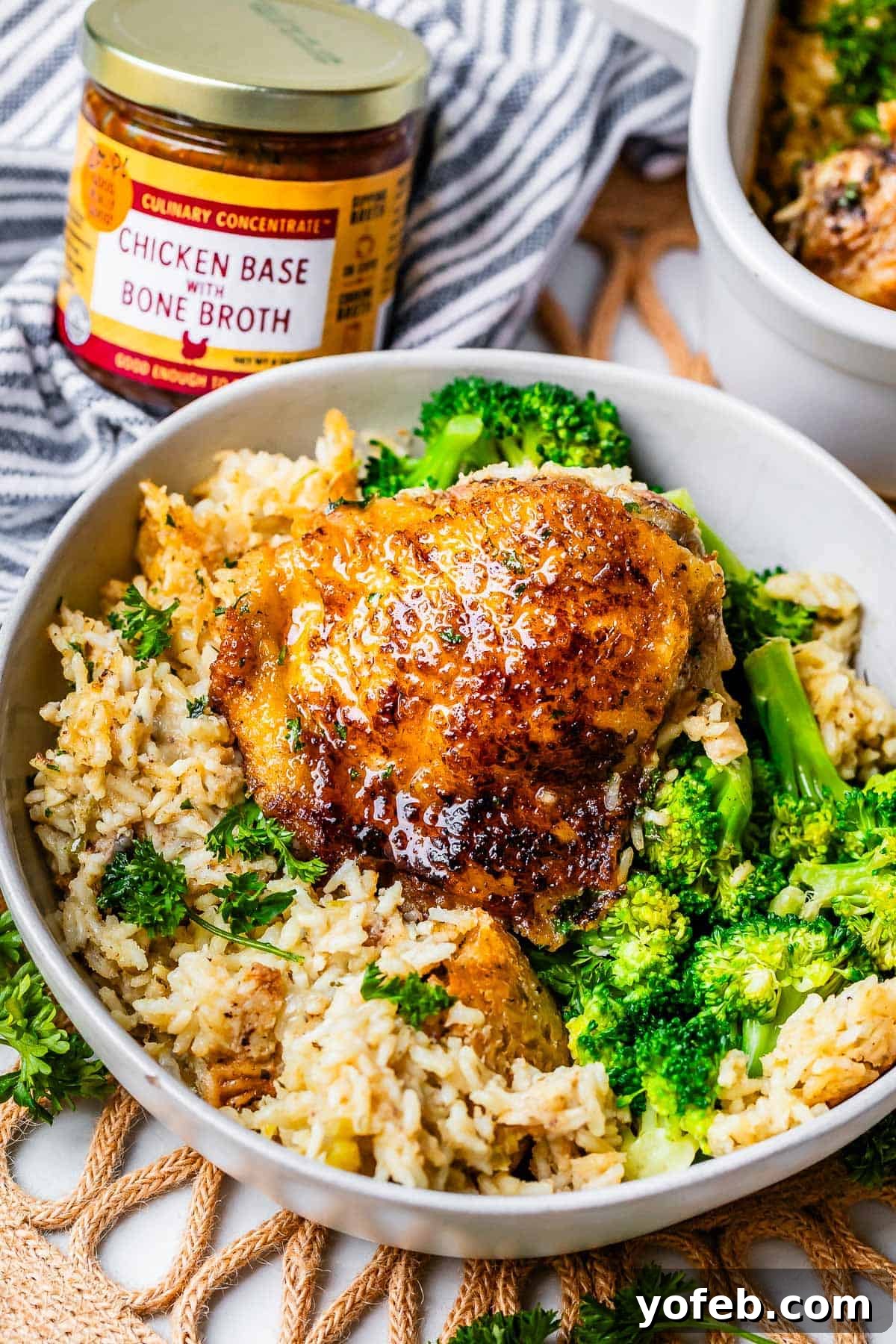 Grandma Georgia's Homestyle Chicken and Rice Bake 20 A well-seared chicken thigh is showcased on a bed of creamy rice, with a side of steamed broccoli, presented in a rustic bowl. This image highlights the comforting and visually appealing nature of the homemade chicken and rice casserole.