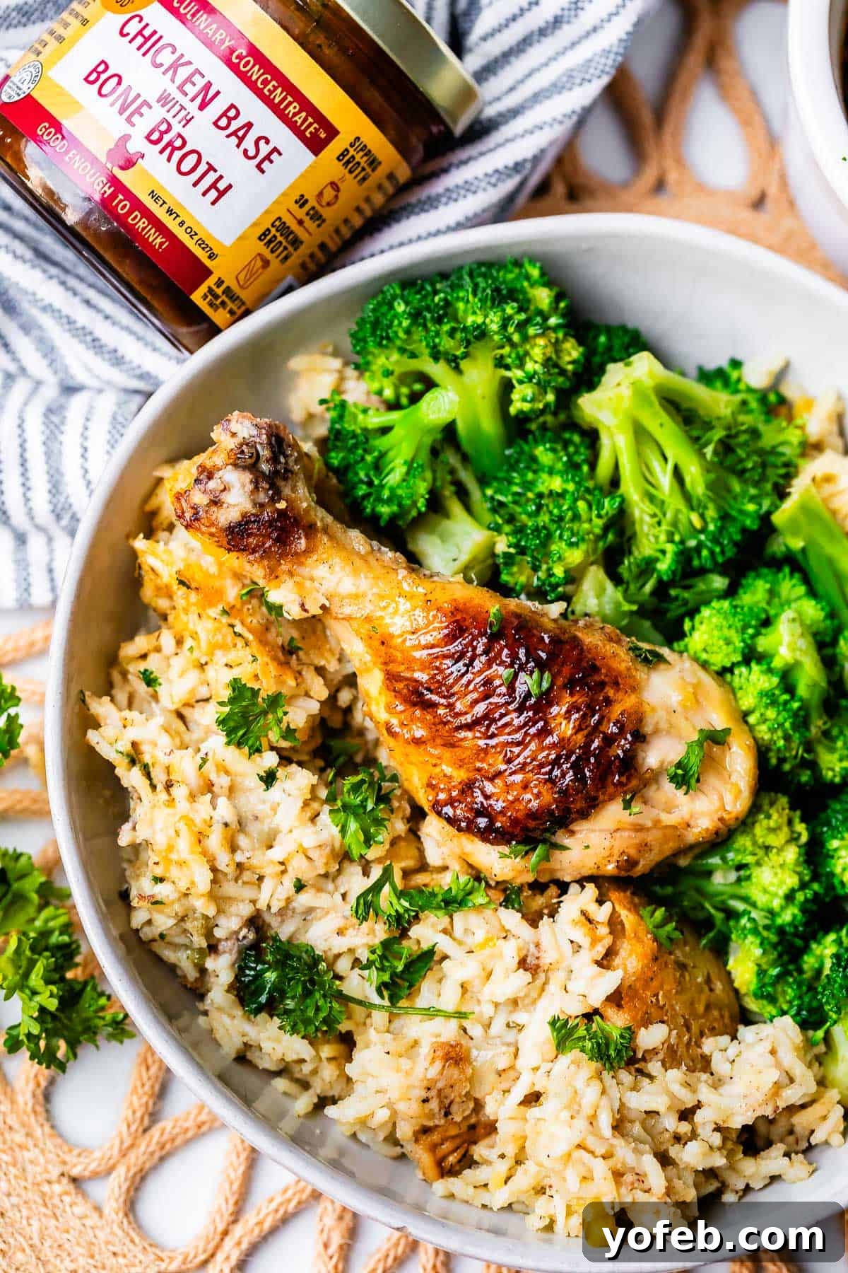 Grandma Georgia's Homestyle Chicken and Rice Bake 22 A browned chicken drumstick, perfectly cooked with a crispy skin, resting on a bed of fluffy rice from the casserole, accompanied by vibrant broccoli in a ceramic bowl. This highlights the comforting and visually appealing nature of the dish.