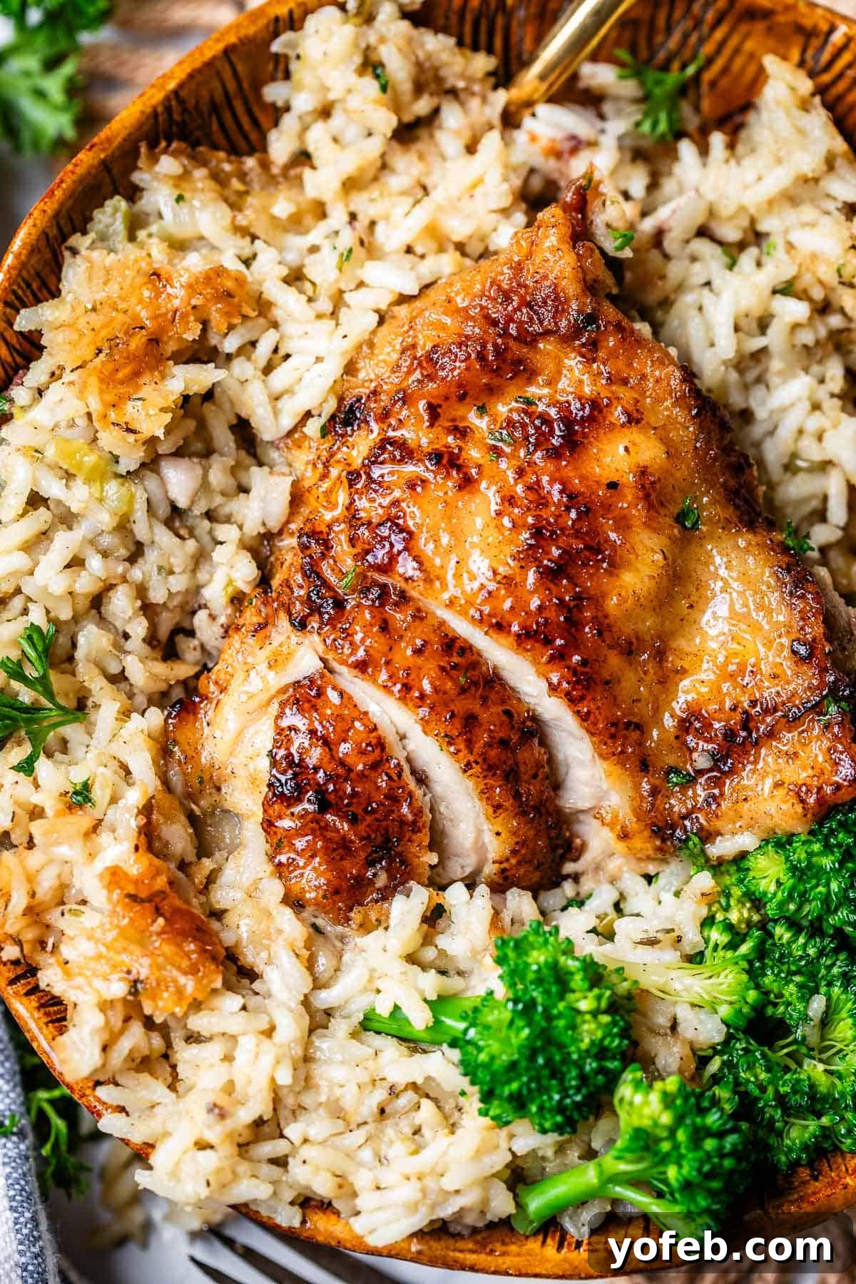 Grandma Georgia's Homestyle Chicken and Rice Bake 24 sliced chicken thigh in a bed of rice with broccoli in a wooden bowl.