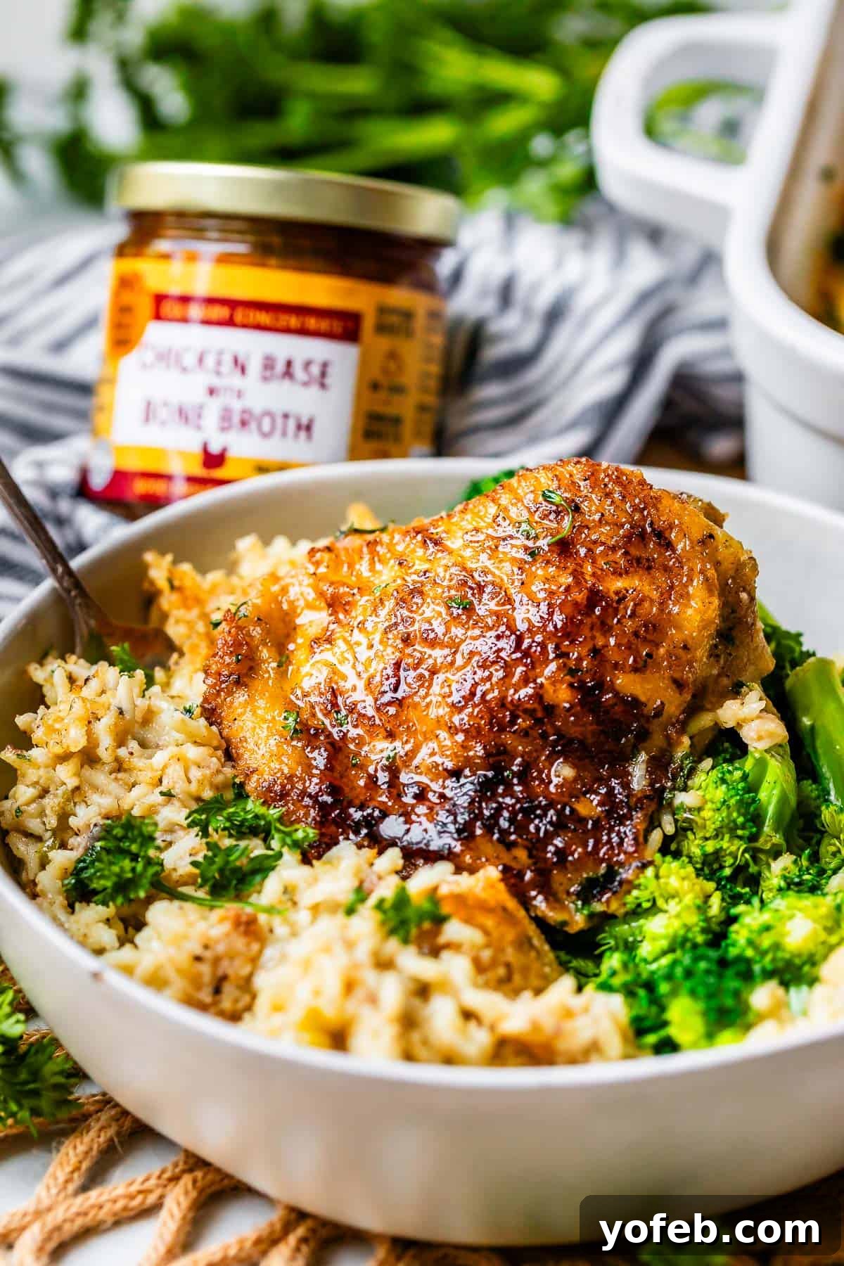 Grandma Georgia's Homestyle Chicken and Rice Bake 6 A ceramic bowl brimming with a generous serving of homemade chicken and rice casserole, accompanied by fresh, steamed broccoli. This image emphasizes the wholesome and comforting nature of the dish, perfect for a family dinner.