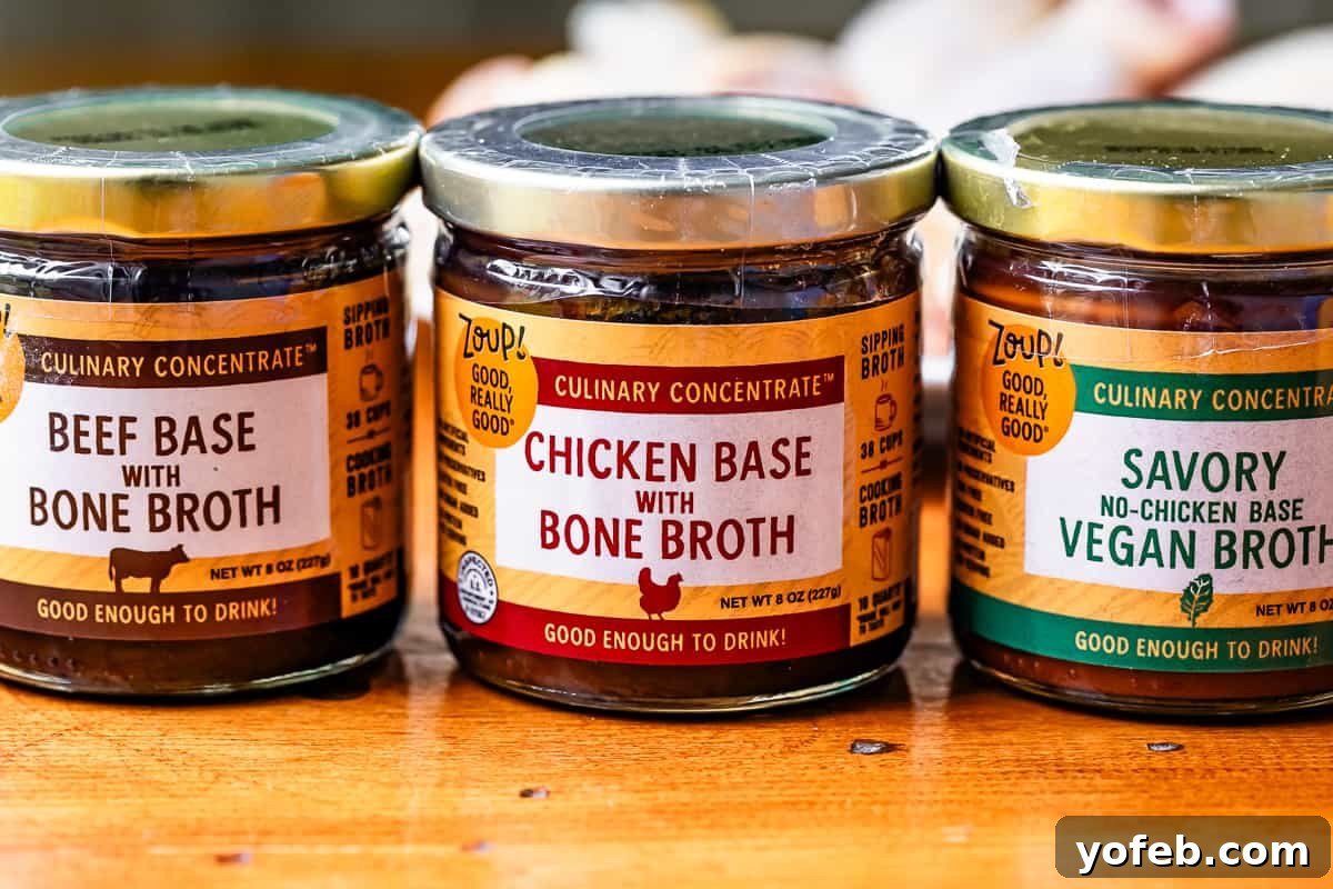 Grandma Georgia's Homestyle Chicken and Rice Bake 9 Three jars of Zoup! Culinary Concentrate, featuring Chicken, Beef, and Vegan broth bases, neatly arranged on a rustic wooden tabletop, ready to add rich flavor to any dish.