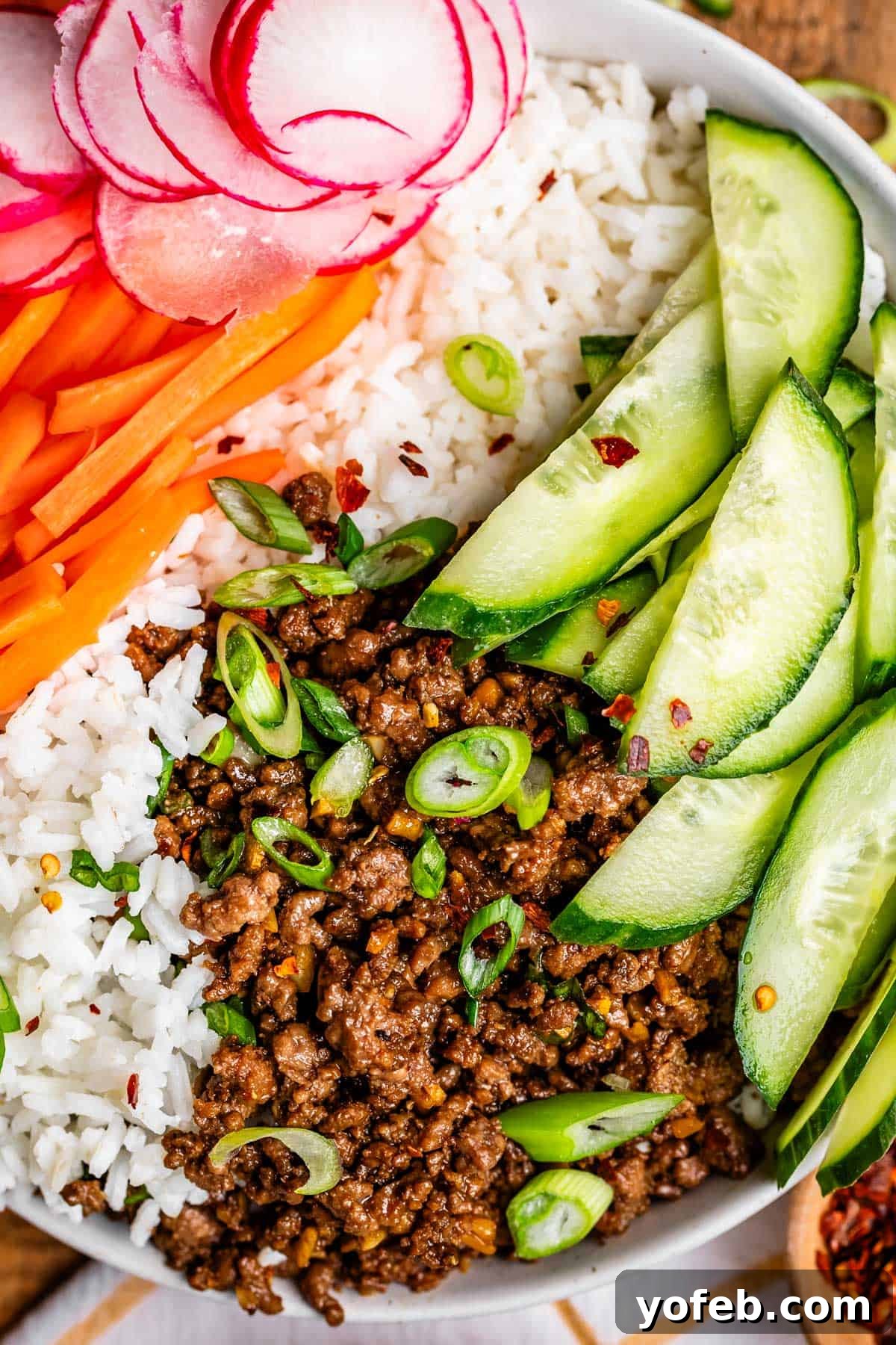 Easy 30-Minute Korean Beef 15 A beautifully arranged Korean beef bowl with rice, savory beef, vibrant sliced cucumbers, fresh radishes, and crisp matchstick carrots.