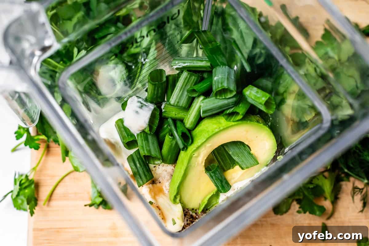 The Ultimate Green Goddess Salad 11 looking into the inside of a blender filled with yogurt, green onion, avocado, and more.