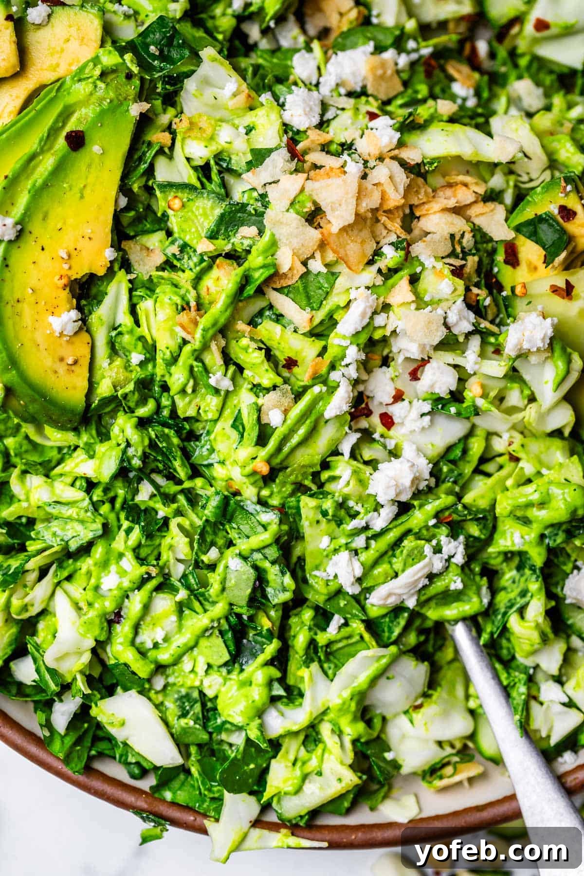The Ultimate Green Goddess Salad 15 fork digging into green goddess salad with avocado and feta cheese on top.