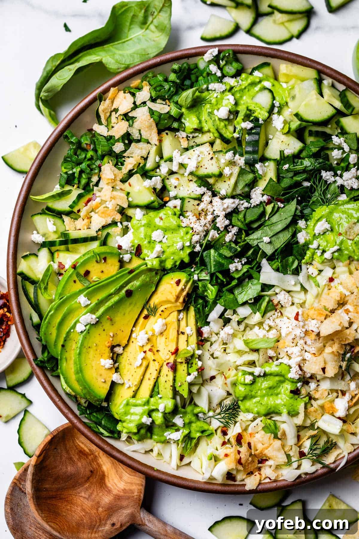 The Ultimate Green Goddess Salad 17 chopped salad topped with green goddess dressing on a plate with avocado and chips.