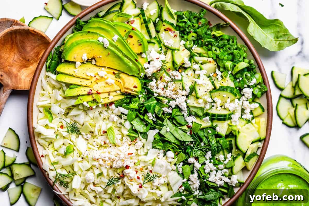 The Ultimate Green Goddess Salad 5 salad with cabbage, spinach, cucumber, green onion, avocado, and feta on a ceramic plate.