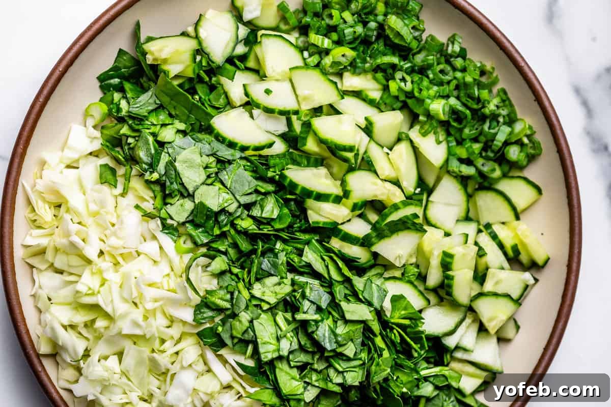 The Ultimate Green Goddess Salad 8 finely chopped cabbage, spinach, cucumber, and green onion on a ceramic plate.