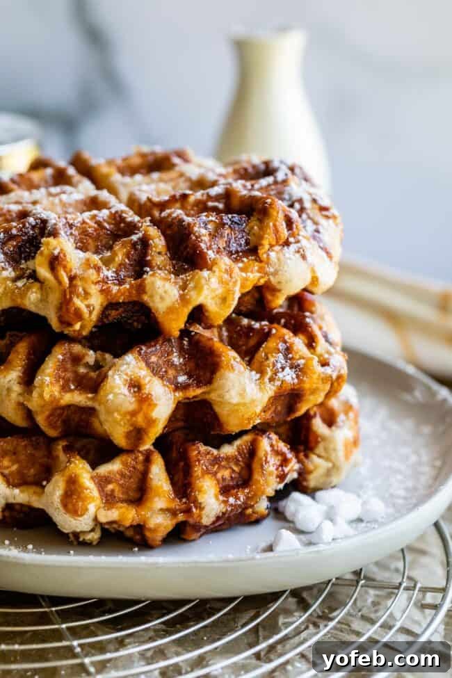 Stack of Pearl Sugar Waffles A delectable stack of Liege waffles, lightly dusted with powdered sugar and adorned with visible pearl sugar crystals, inviting a sweet indulgence.