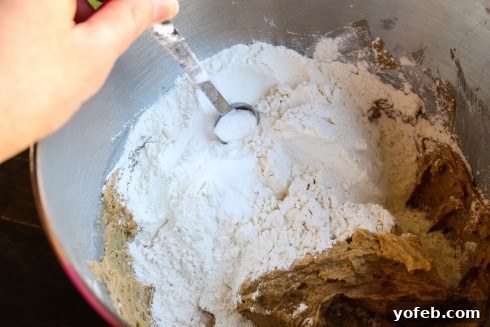 Decadent Caramel Butterscotch Cookies 10 The process of mixing dry ingredients into wet ingredients in a large bowl, showing the texture of the cookie dough.