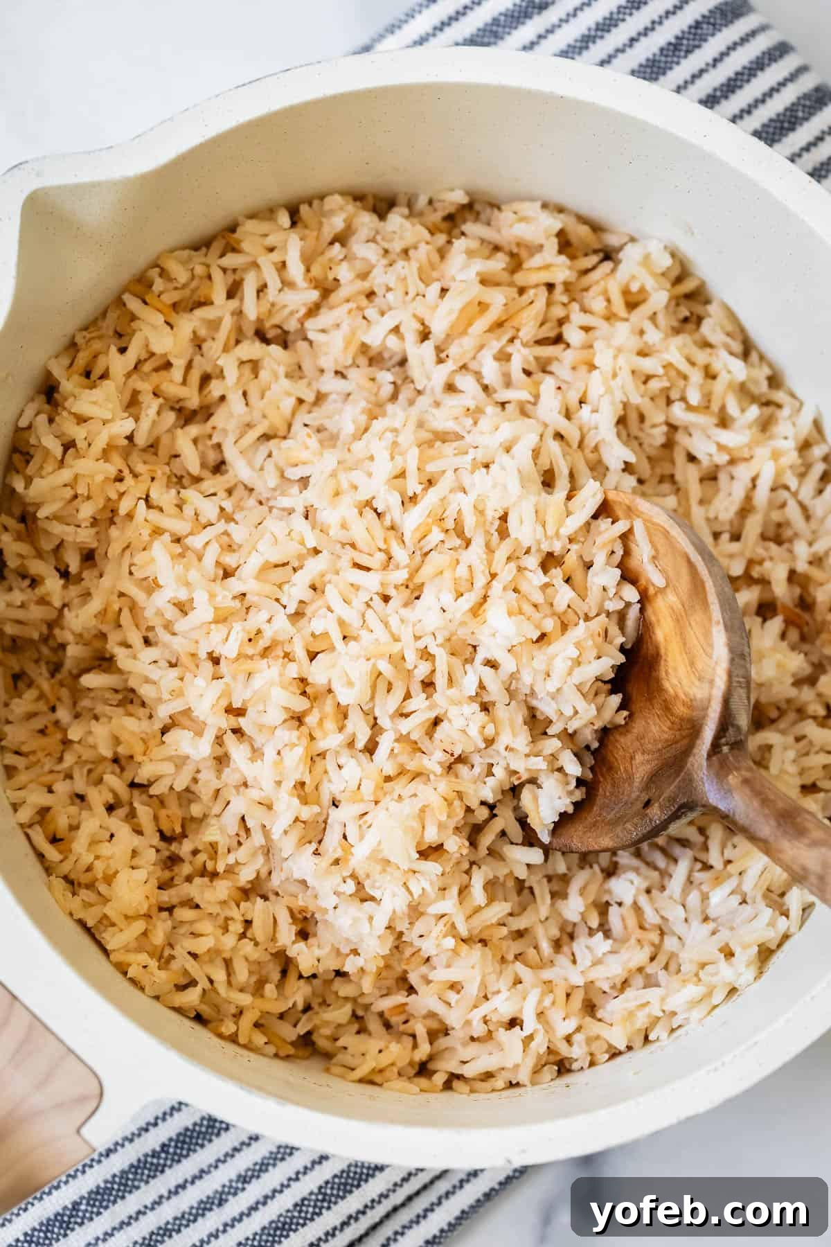 Perfect Stovetop Rice Every Time 16 Toasted white rice cooked with browned butter in a white pot, stirred with a wooden spoon, showcasing its rich, golden color.