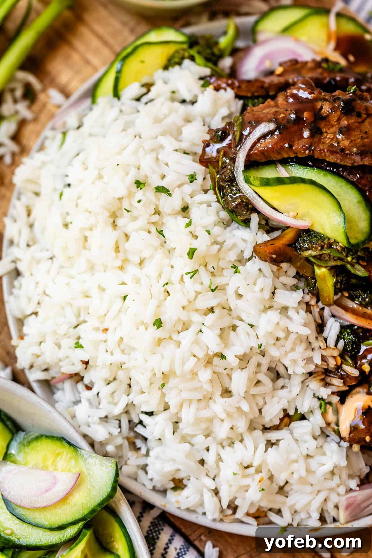 Perfect Stovetop Rice Every Time 3 Cooked rice on plate with savory beef and crisp broccoli, garnished with cucumbers for a balanced meal.