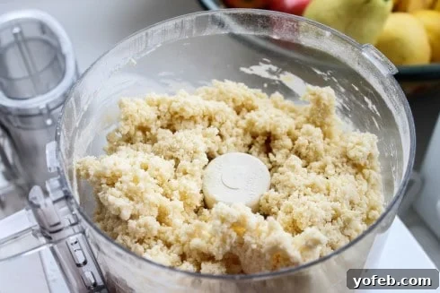 Moist crumbs forming after adding egg and cream to the tart shell mixture, with visible butter bits.
