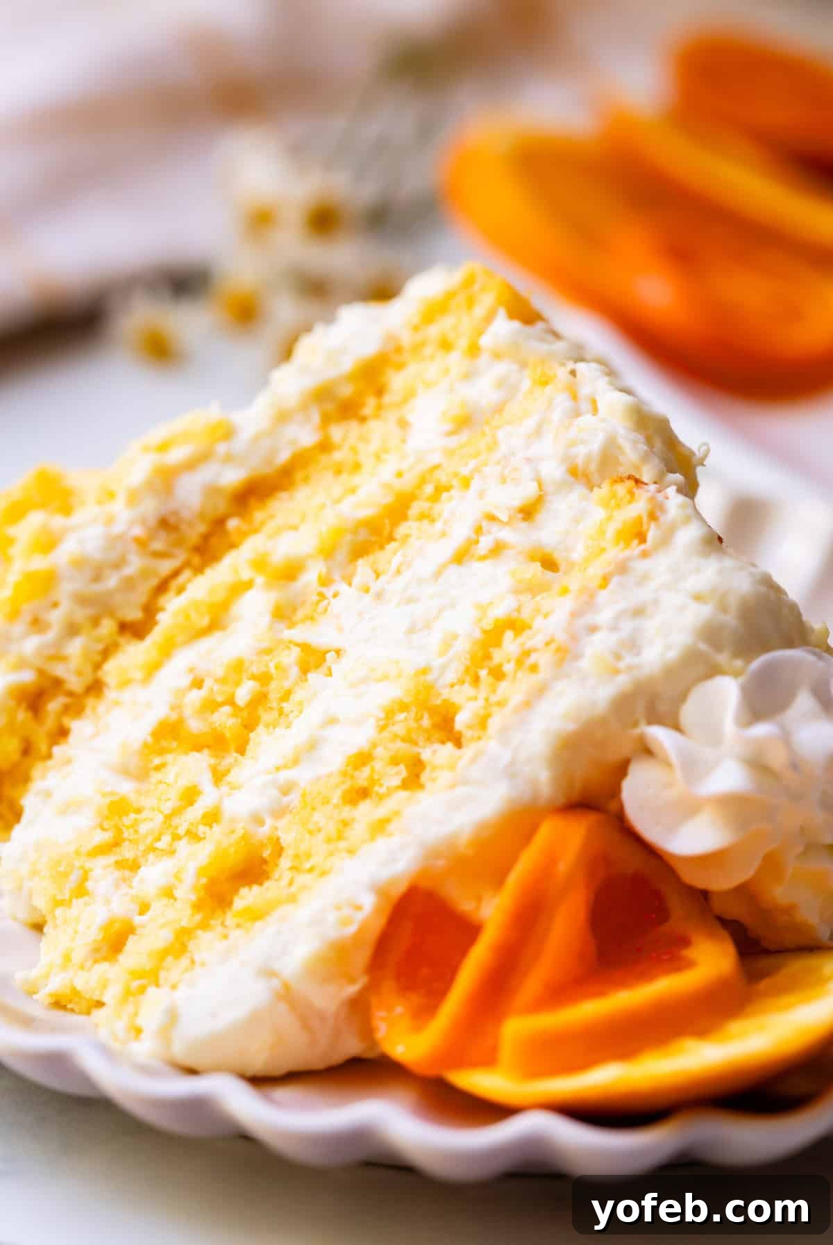 Golden Pineapple Mandarin Cake 20 slice of caking lying on its side on a ceramic plate, with orange slices as garnish on top.