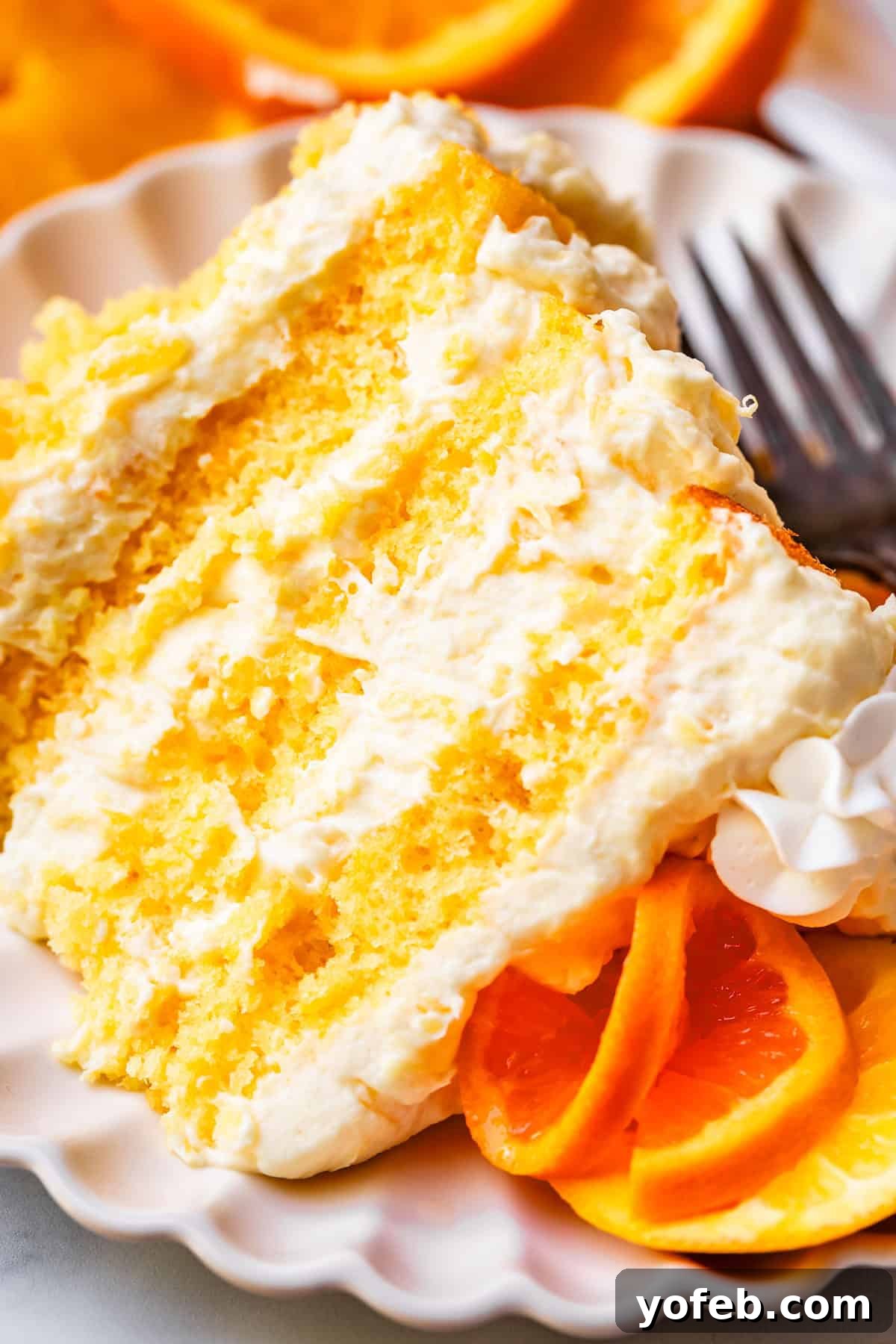 Golden Pineapple Mandarin Cake 6 slice of sunshine cake showing all the layers on a ceramic plate with a metal fork.