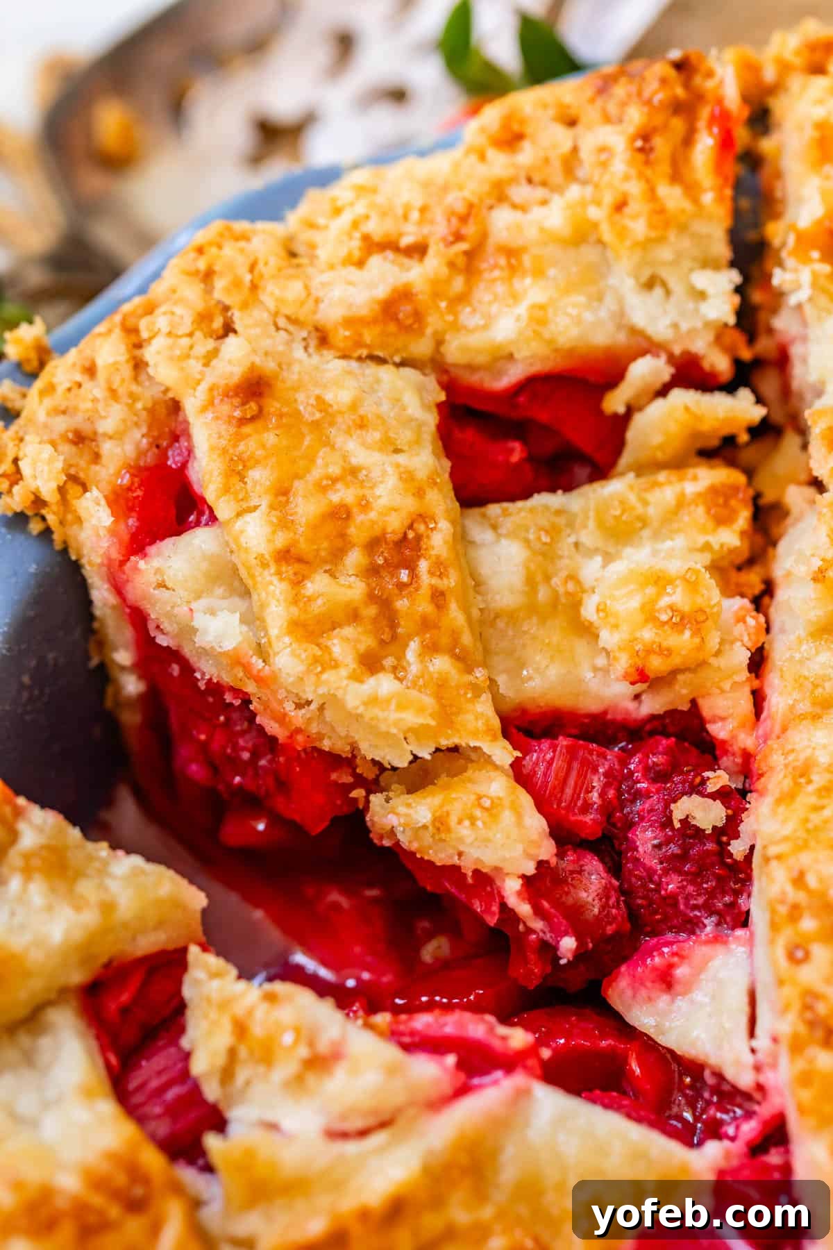 Summer's Sweet & Tart Strawberry Rhubarb Pie 28 a piece of strawberry rhubarb pie in the pan with flaky lattice crust.