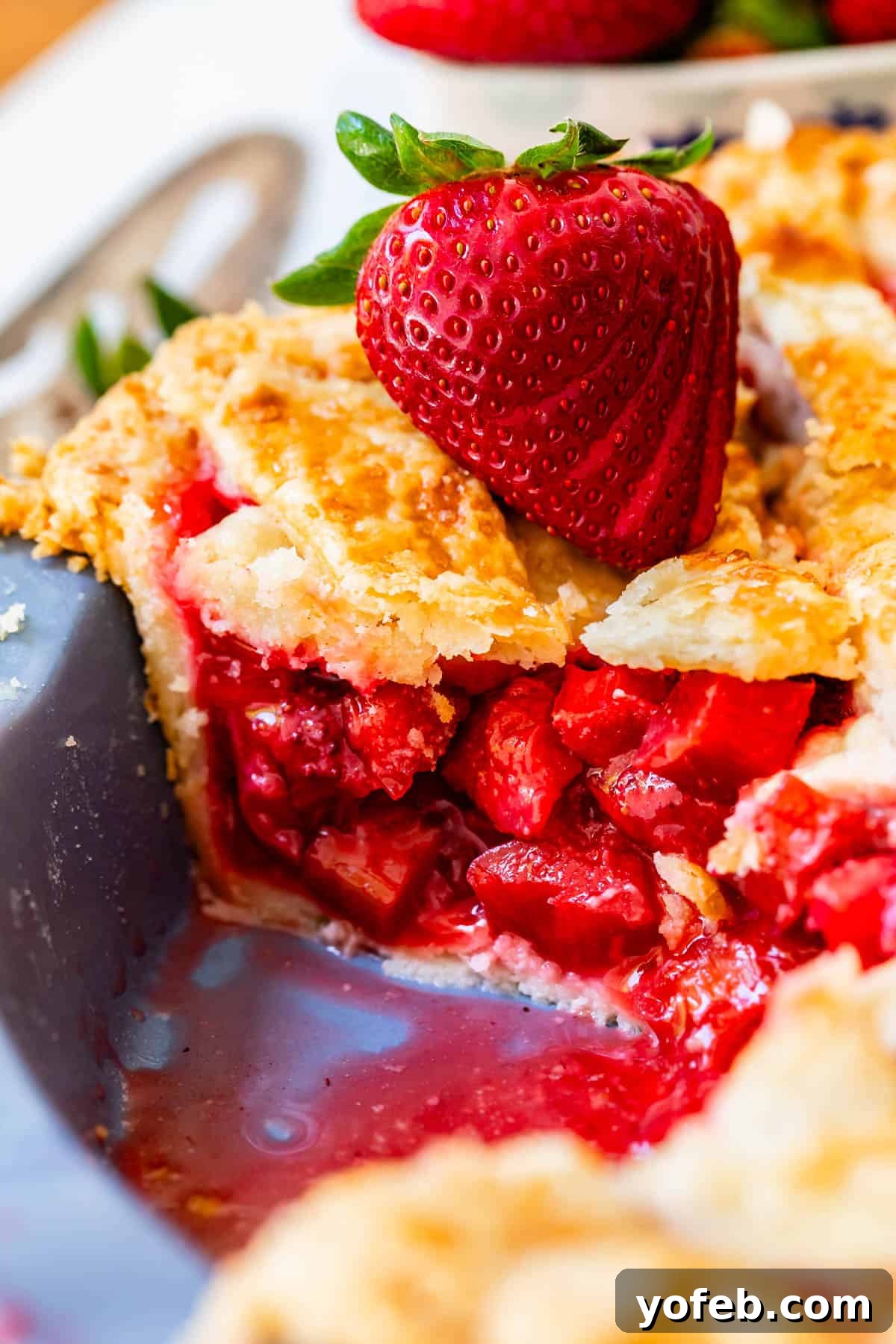 Summer's Sweet & Tart Strawberry Rhubarb Pie 29 side view with all the strawberry rhubarb filling of a piece of pie in a pie pan with strawberry garnish.