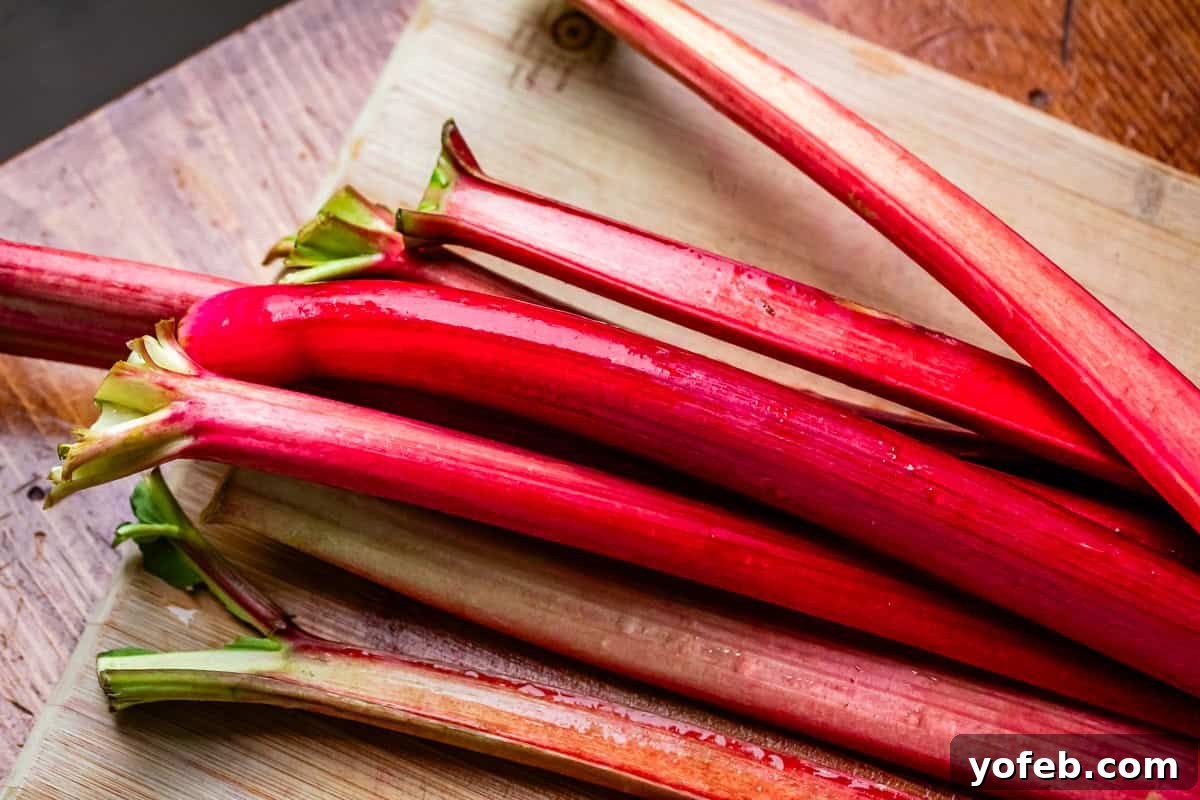 Summer's Sweet & Tart Strawberry Rhubarb Pie 6 looking down at a bunch of about 7 or 8 whole stalks of rhubarb on a wooden cutting board.