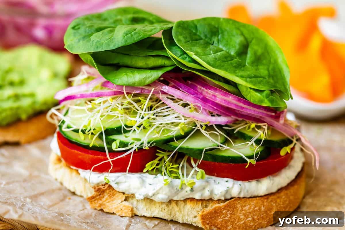 Vibrant Vegetable Stack 17 sourdough slice topped with spread, tomato, cucumber, sprouts, pickled onion, and spinach.