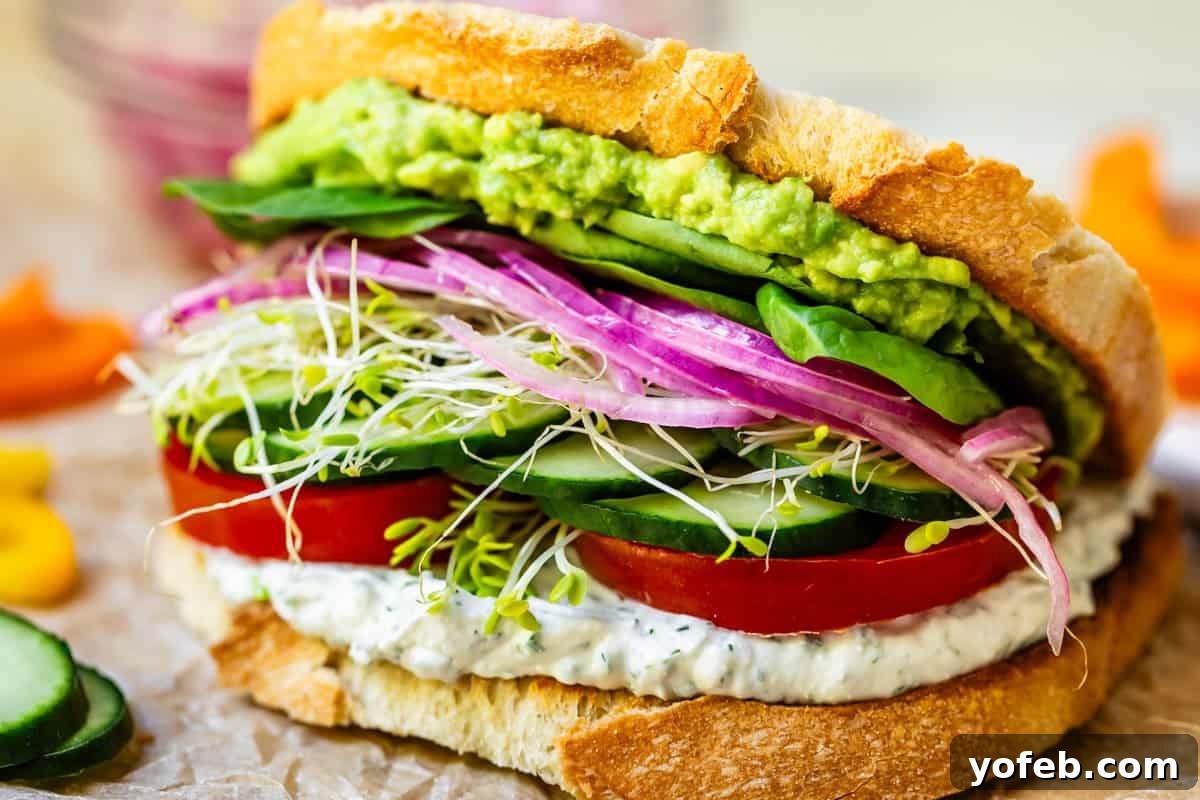 Vibrant Vegetable Stack 18 a full veggie sandwich with spread and smashed avocado, and lots of veggies layered between.