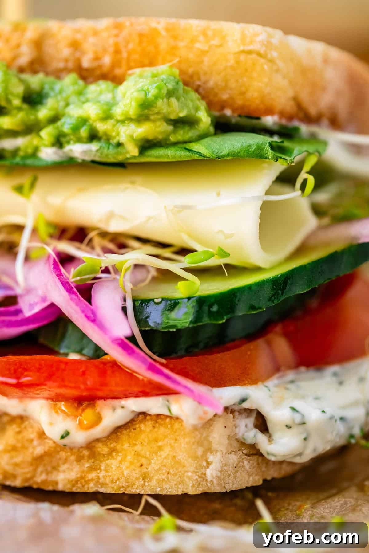 Vibrant Vegetable Stack 20 veggie sandwich with spread, tomato, cucumber, onion, sprouts, cheese, and guac layers.