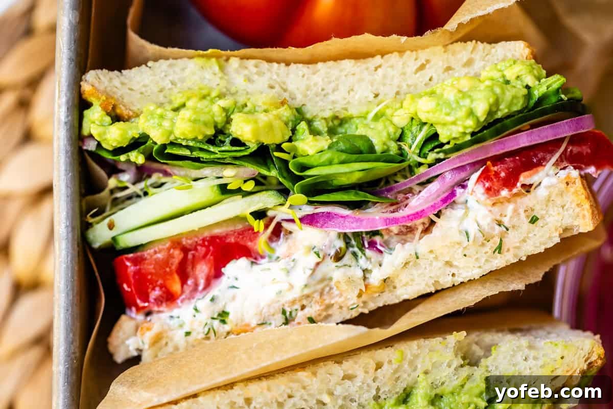 Vibrant Vegetable Stack 3 close up of the cut side of a fresh vegetable sandwich with all the fixings in parchment paper.