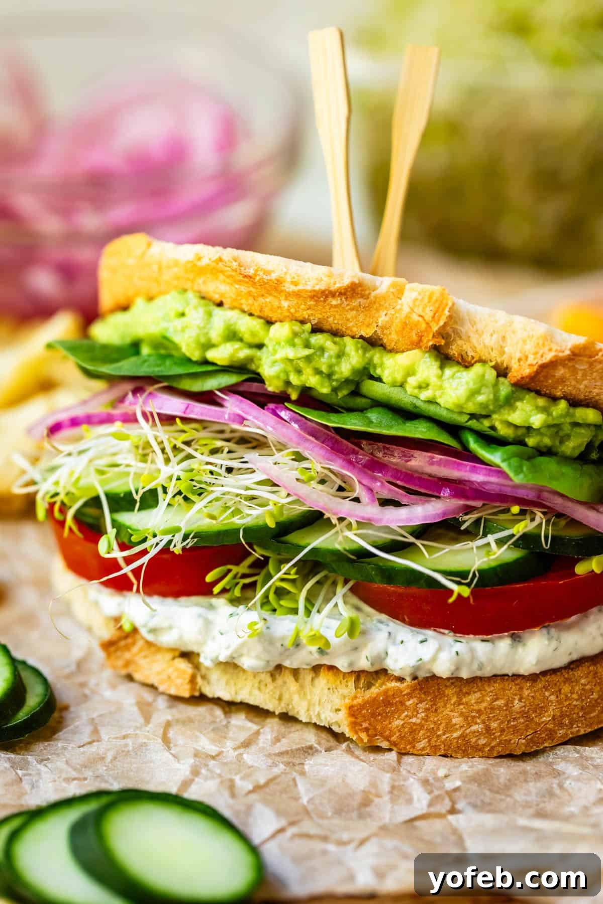 Vibrant Vegetable Stack 23 a delicious fresh veggie sandwich with 2 bamboo sandwich skewers in the top on parchment paper.
