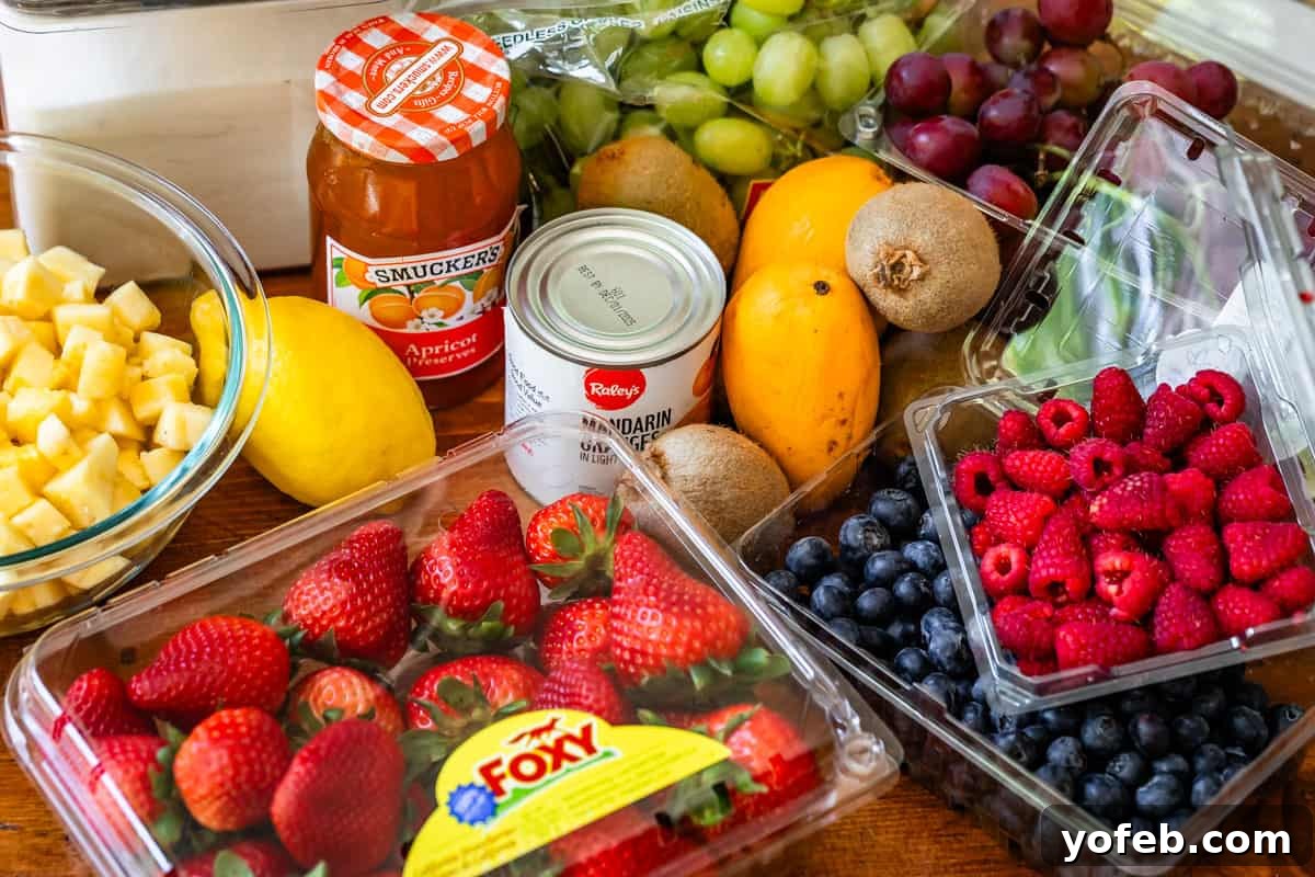 A beautiful flat lay of fresh fruit salad ingredients, including a variety of berries, vibrant mango, and a jar of apricot preserves, ready for preparation.
