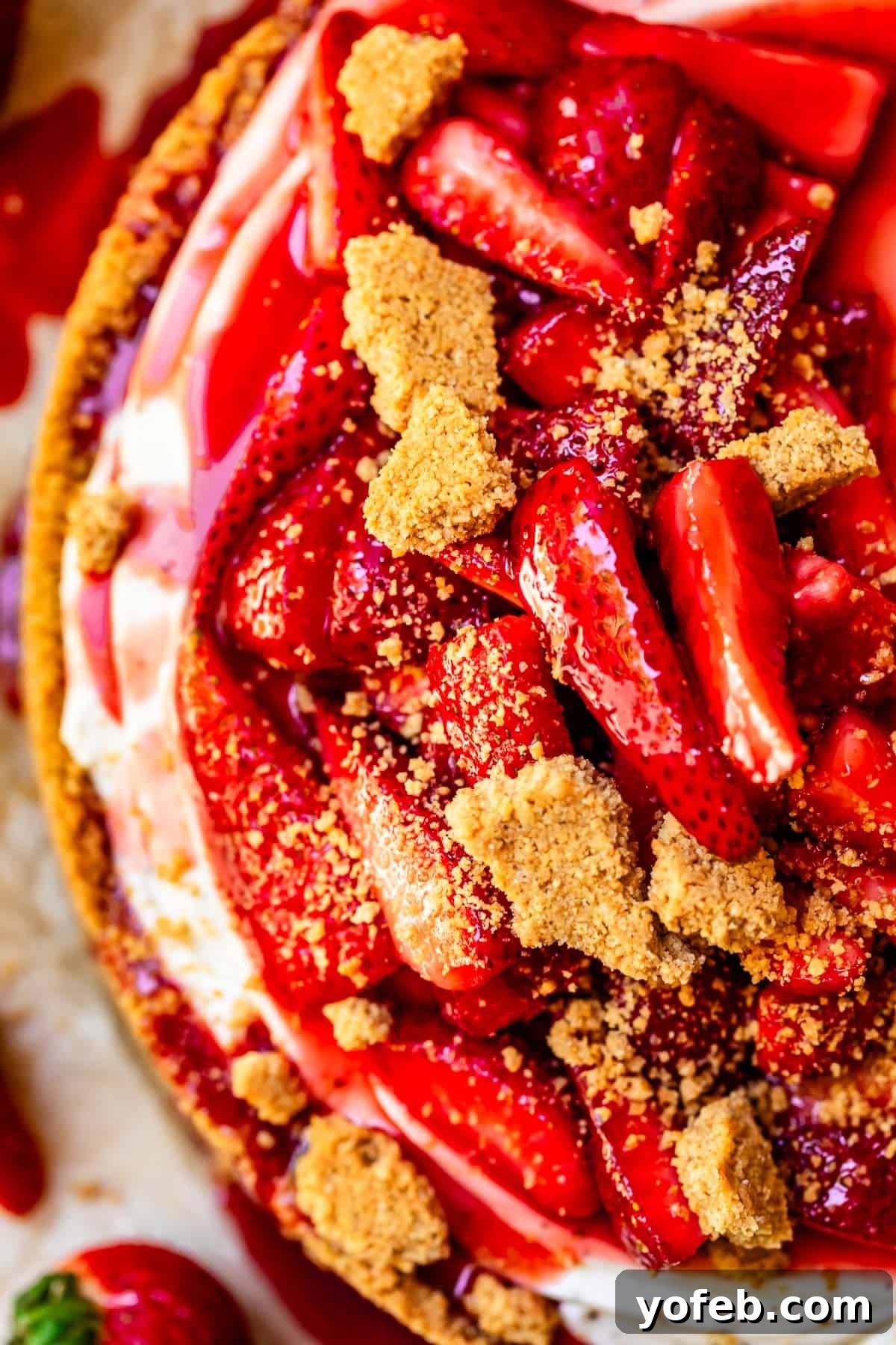 The Ultimate No Bake Cheesecake 11 angle looking down at the top of a no bake cheesecake with strawberry topping and graham crumble.