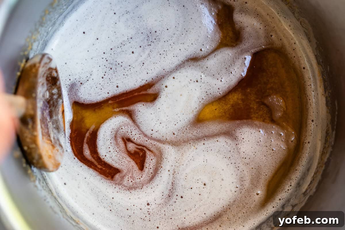 The Ultimate No Bake Cheesecake 12 a wooden spoon in a metal pot stirring browned butter with light foam on top.