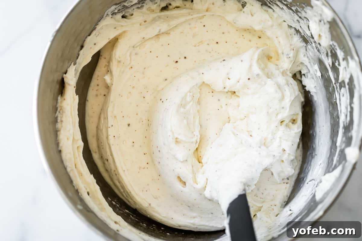 The Ultimate No Bake Cheesecake 27 cheesecake filling with flecks of browned butter bits, in a metal mixing bowl.