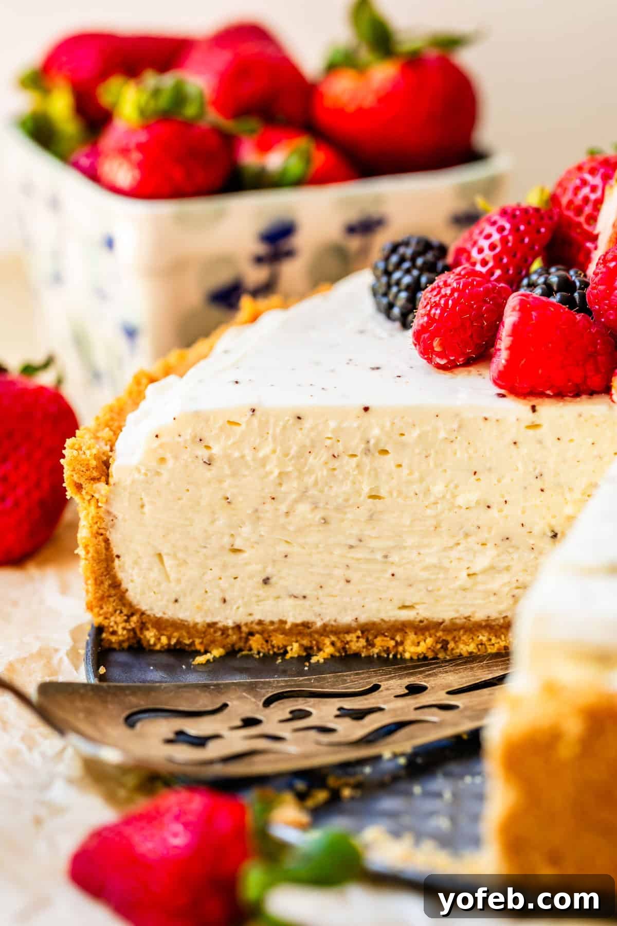 The Ultimate No Bake Cheesecake 33 side view of a no bake cheesecake with a piece cut out of it and fresh berry topping.