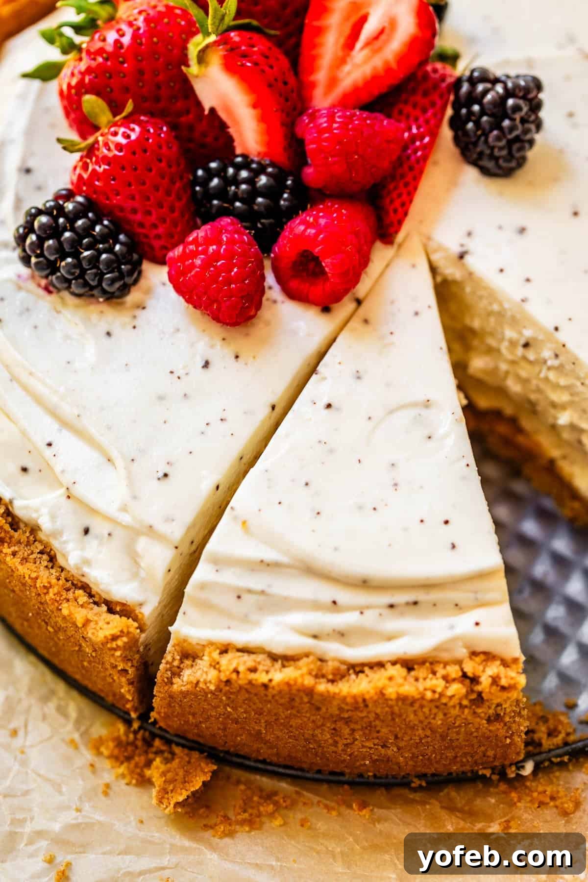 The Ultimate No Bake Cheesecake 10 no bake cheesecake with fresh berry garnish, with one slice missing and a second slice cut.
