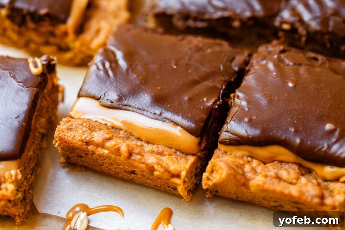 Classic Cafeteria Peanut Butter Bars 3 Two generously frosted peanut butter lunch lady bars with a visible oatmeal cookie base, arranged on parchment paper, highlighting their delightful layers.