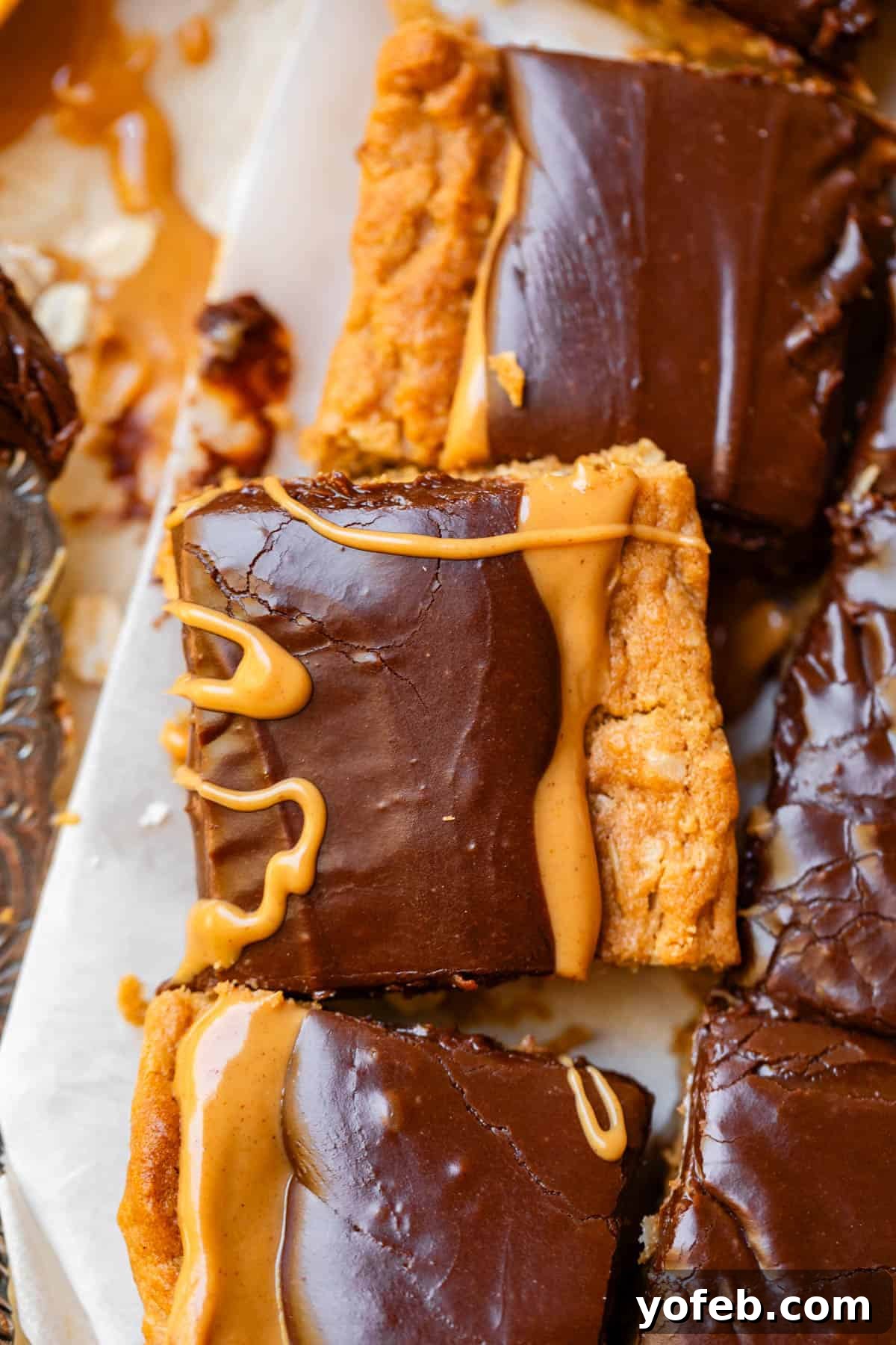 Classic Cafeteria Peanut Butter Bars 23 Neatly cut squares of peanut butter cookie bars arranged on parchment paper, each drizzled with extra peanut butter for added flavor and visual appeal.