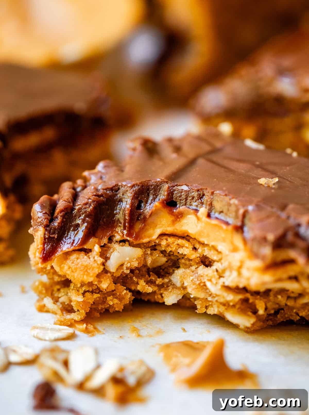 Classic Cafeteria Peanut Butter Bars 5 A single square of a Lunch Lady Peanut Butter Bar on parchment paper, with a tempting bite taken out, revealing its soft layers.