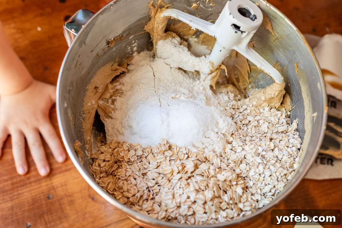 Classic Cafeteria Peanut Butter Bars 10 A metal mixing bowl on a kitchen counter, filled with the dry ingredients for the oatmeal cookie base, including flour, oats, baking soda, and salt, ready to be combined.